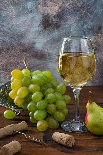 Vaso con vino blanco, racimo de uvas y sacacorchos de mesa de madera. Ã Â¡lose-up.