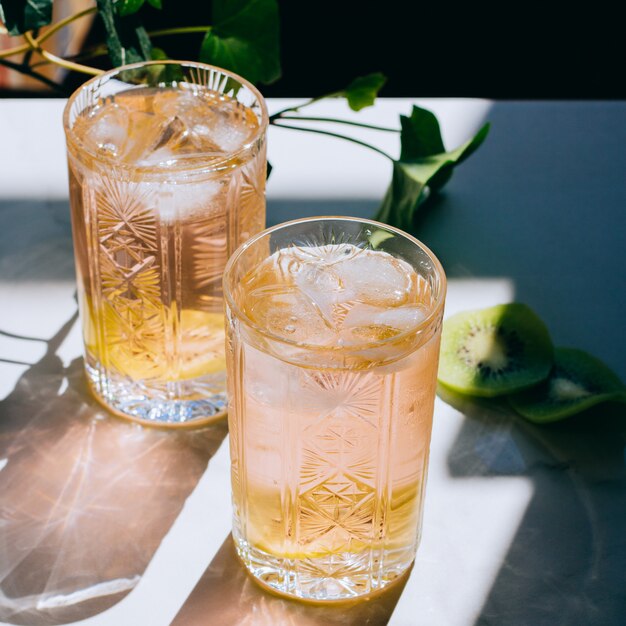 Un vaso de vino rosado en un vaso de cristal sobre mármol, hiedra verde y sol brillante