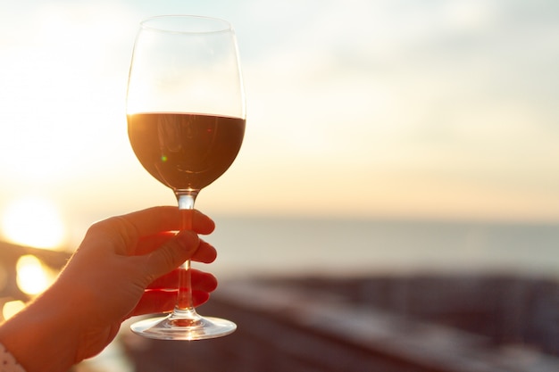 Un vaso de vino tinto al atardecer.