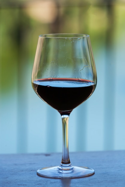 Foto un vaso de vino tinto en una mesa de madera, una hermosa naturaleza en el fondo