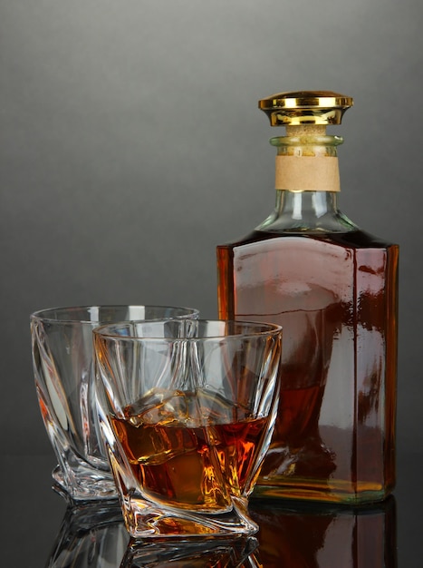 Vaso de whisky con botella sobre fondo oscuro