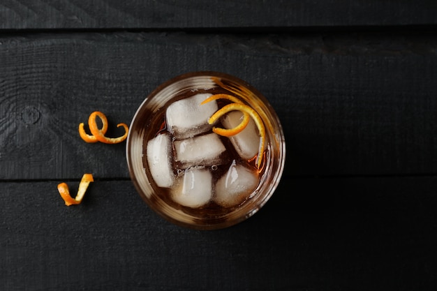 Vaso de whisky y cáscara de naranja en madera