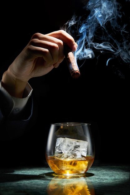 Un vaso de whisky y un cigarro con humo.