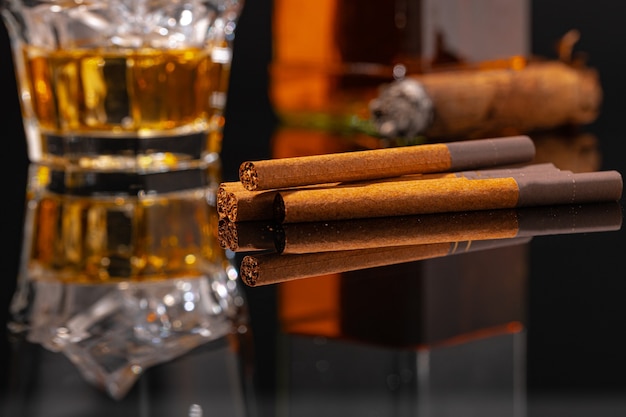 Vaso de whisky y cigarro en mesa negra