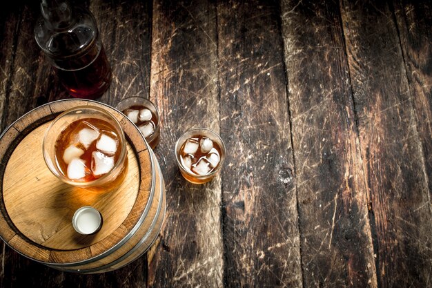 Vaso de whisky escocés con barril. Sobre un fondo de madera.