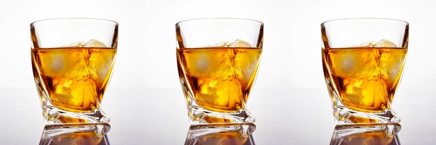 Vaso de whisky escocés con hielo sobre un fondo blanco.