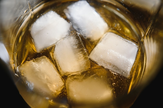 Vaso de whisky escocés y hielo sobre negro