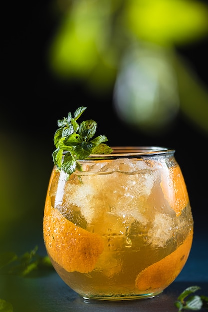 Un vaso de whisky escocés con jugo de naranja y decoración con menta fresca