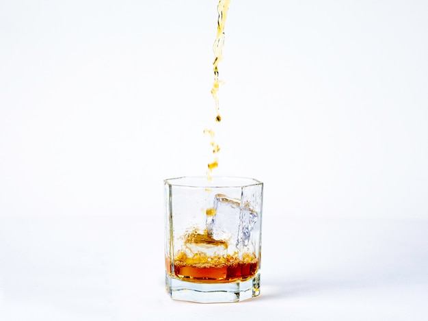 El vaso de whisky con hielo fresco sobre el fondo blanco