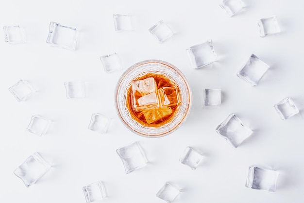 Vaso de whisky con hielo sobre un fondo blanco con lugar para texto