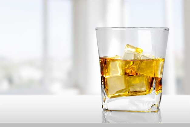 Vaso de whisky con hielo sobre fondo claro