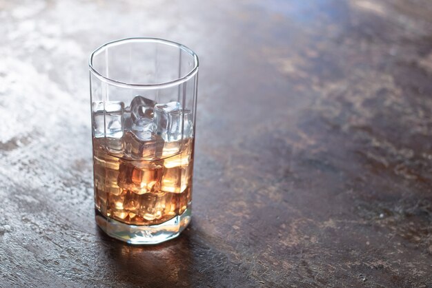 Vaso de whisky con hielo sobre fondo negro