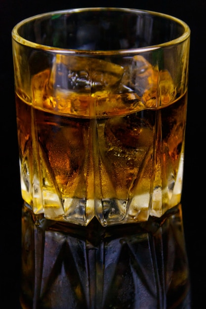 Vaso de whisky con hielo sobre un fondo negro