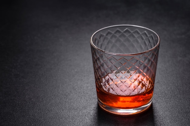 Un vaso de whisky o coñac sobre una mesa de hormigón negro Tiempo de relajación