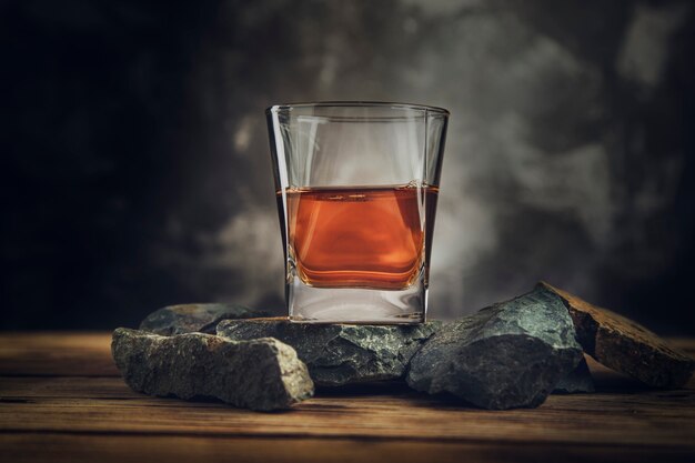 Foto vaso de whisky en piedra en la oscuridad