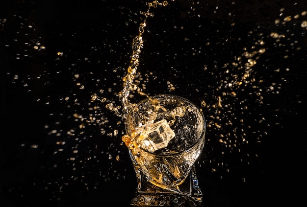 Vaso de whisky con salpicaduras de los cubitos de hielo.