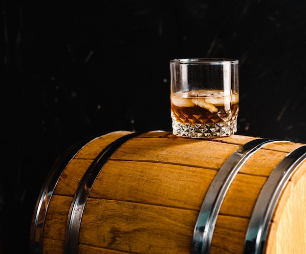 Un vaso de whisky sentado en un barril de madera.