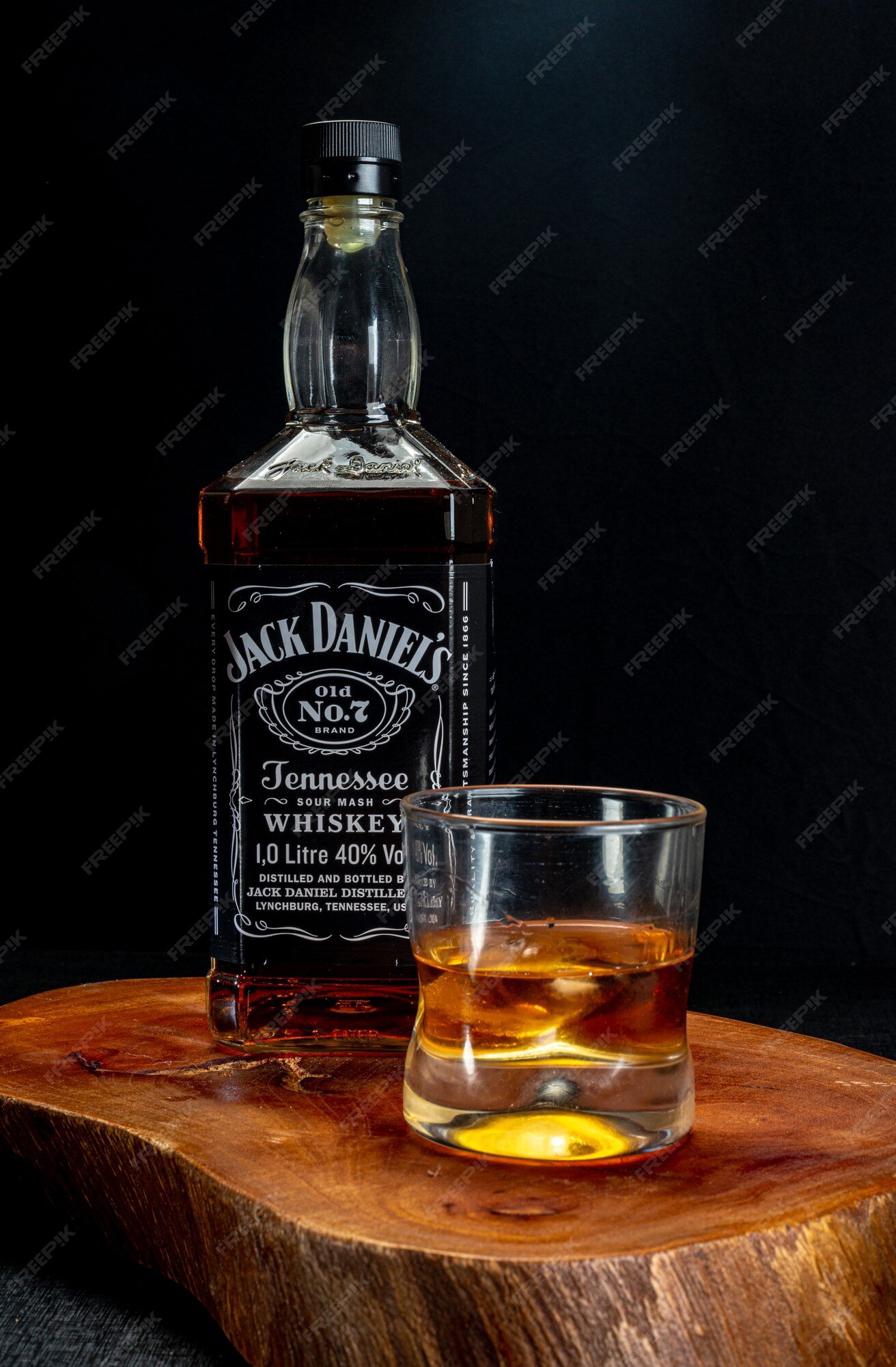 Medición diario desmayarse Vaso de whisky servido con hielo y una botella de jack daniels en madera  rústica sobre fondo negro | Foto Premium