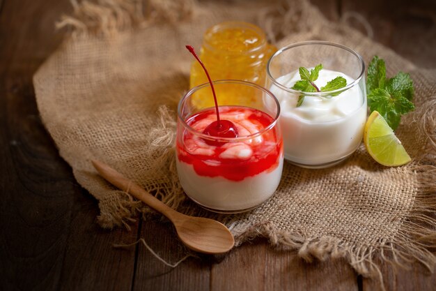 Vaso de yogur de cereza y yogur de menta y limón sobre una mesa de madera marrón