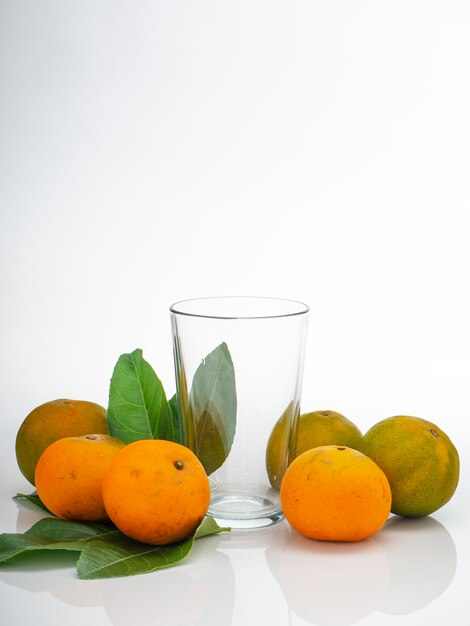 Vaso con zumo de naranja y frutas con hojas verdes.