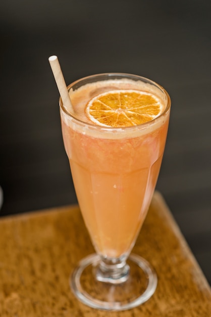 Un vaso de zumo de naranja natural con una pajita de cóctel orgánico sobre la mesa. Cóctel de vitaminas. enfoque selectivo suave.