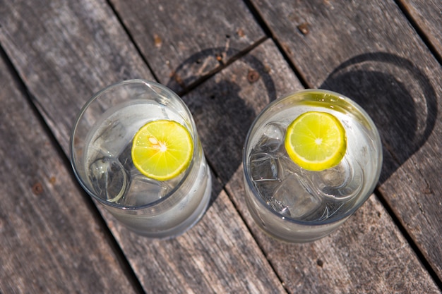 Vasos de agua con limón sobre madera