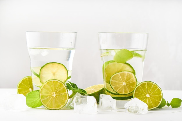 Vasos con agua, rodajas de lima, menta y cubitos de hielo