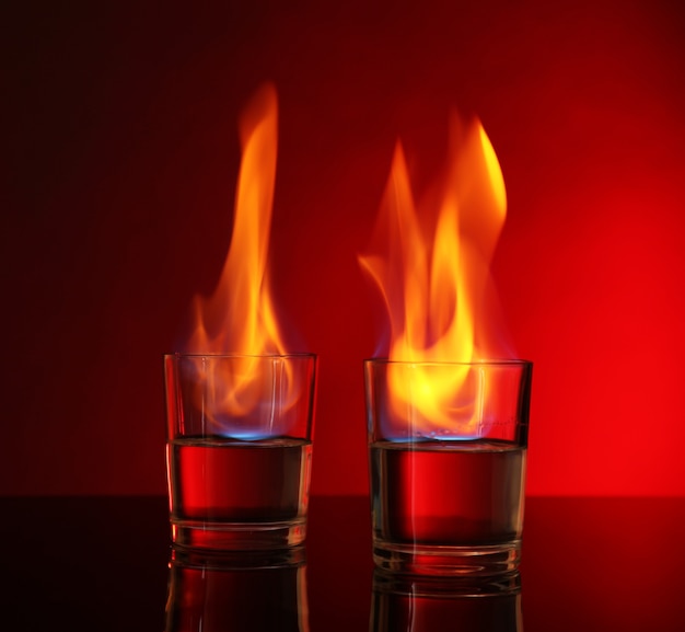 Vasos con alcohol ardiente sobre fondo rojo.