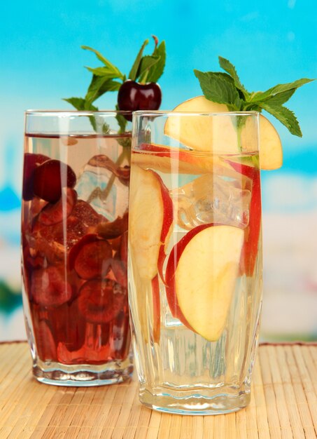 Vasos de bebidas de frutas con cubitos de hielo en azul