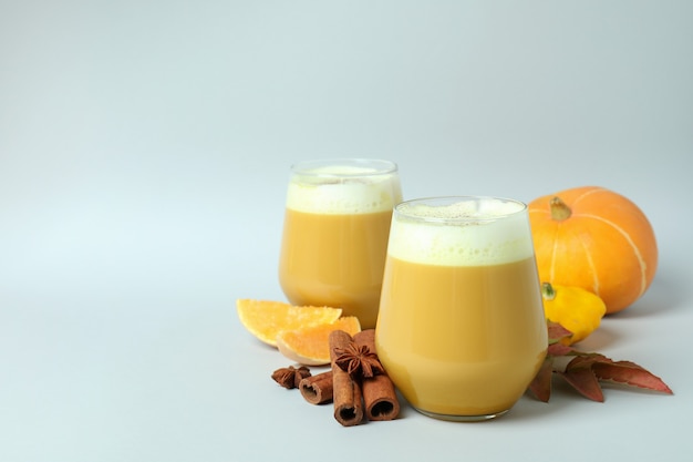 Vasos de calabaza con leche e ingredientes sobre fondo gris claro