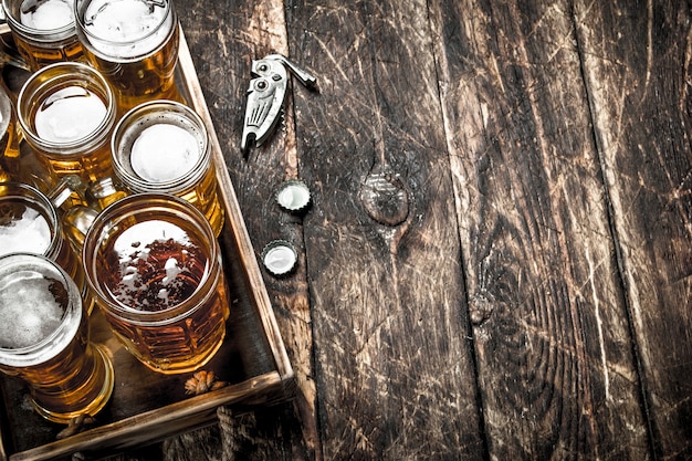 Vasos con cerveza fresca en una bandeja vieja. Sobre una mesa de madera.