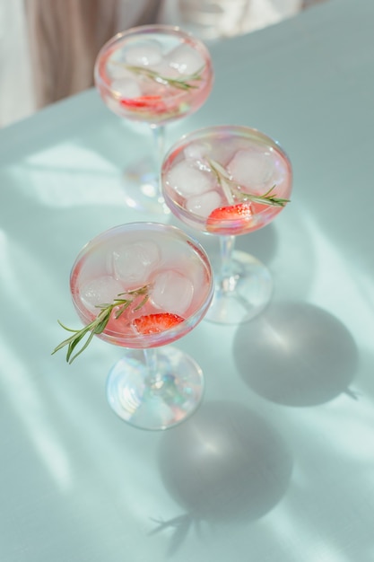 Vasos de cóctel de fresa o cóctel sin alcohol, refrescante bebida de verano con hielo picado y agua con gas en azul claro