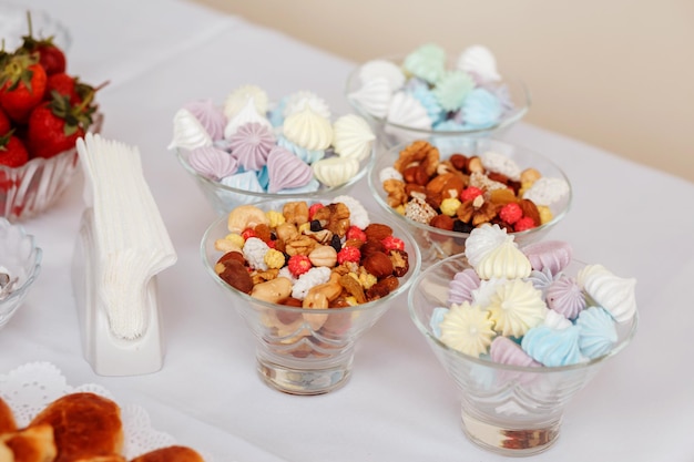 Vasos com diferentes doces na mesa, como frutos secos de nozes merengues