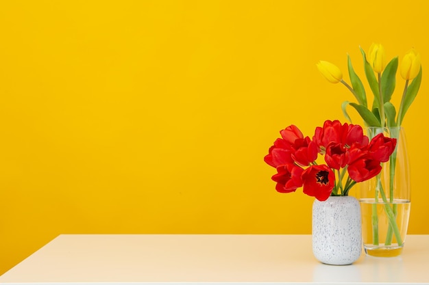 Vasos com tulipas em fundo amarelo com espaço para texto