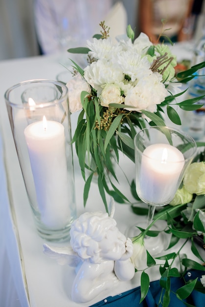 Vasos de vidro com velas brancas ficar na mesa de jantar entre bouquets pastel