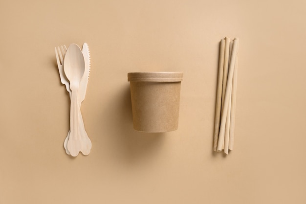 Vasos desechables biodegradables ecológicos y cucharas individuales, tenedores, pajitas de bambú en el espacio beige