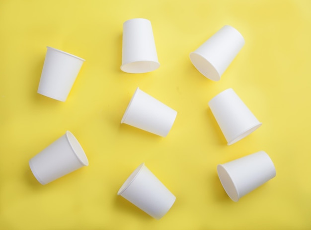 Foto vasos desechables de papel blanco sobre un fondo amarillo vista desde arriba lay plano