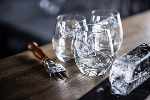 Vasos enfriados para cócteles con hielo con un gran cubo de hielo y un picador de hielo a un lado.