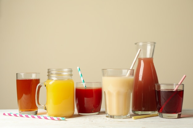 Vasos y frascos con diferentes jugos en la mesa de madera blanca