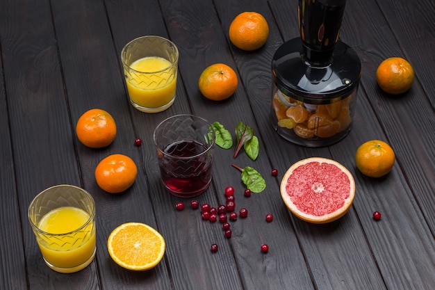 Vasos de jugo de naranja y pomelo con frutas tropicales