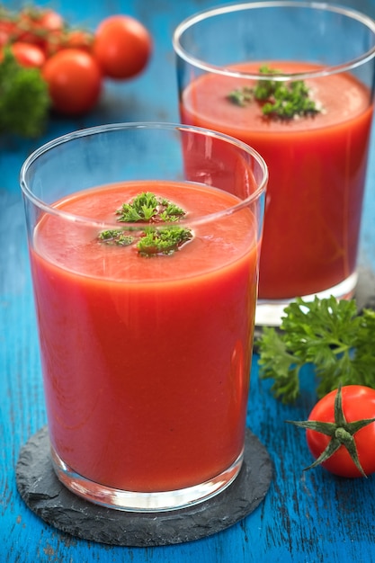 Vasos de jugo de tomate fresco y tomates con perejil