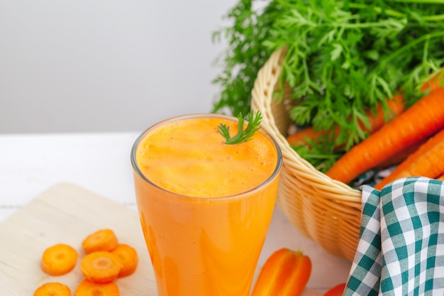 Vasos de jugo de zanahoria con verduras en la mesa de cerca