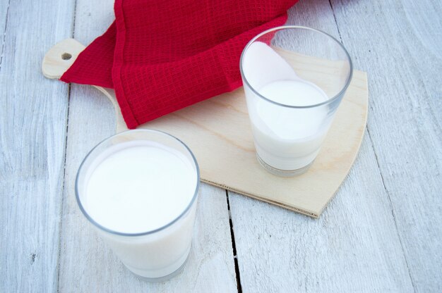 Vasos con leche y toalla roja sobre un fondo claro