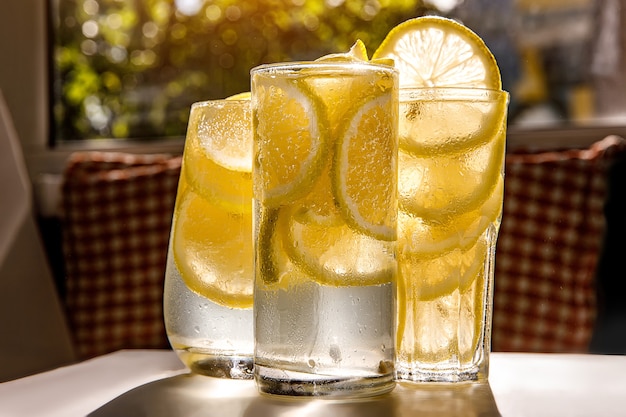 Vasos de limonada con limón en la habitación soleada