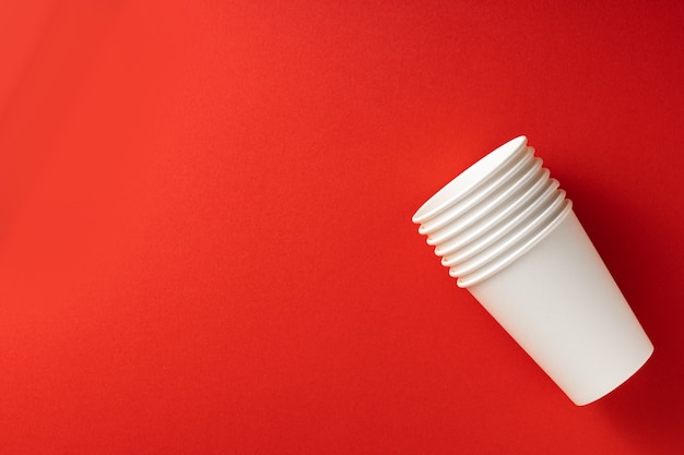 Foto vasos de papel blanco sobre fondo rojo. vista superior lugar para texto concepto de ecología