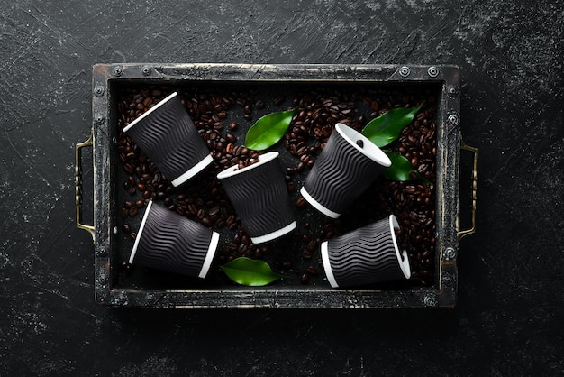 Vasos de papel para café y granos de café Sobre un fondo de piedra negra Vista superior Espacio libre para su texto