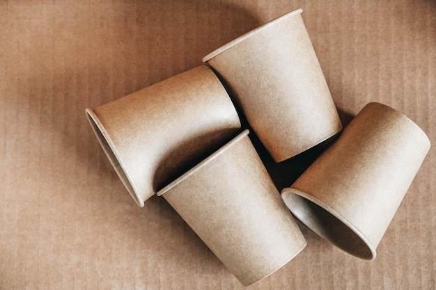 Vasos de papel desechables sobre fondo de papel kraft Vajilla desechable ecológica