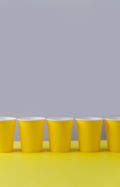 Vasos de papel eco natural amarillo sobre fondo gris amarillento. Concepto de estilo de vida sostenible. cero residuos, sin plástico, detener la contaminación plástica.