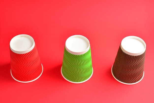 Vasos de papel marrón verde rojo sobre un fondo rojo Copiar espacio