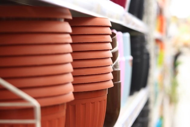 Vasos para plantas em uma prateleira em um supermercado Vasos de plástico marrom empilhados um a um foco seletivo